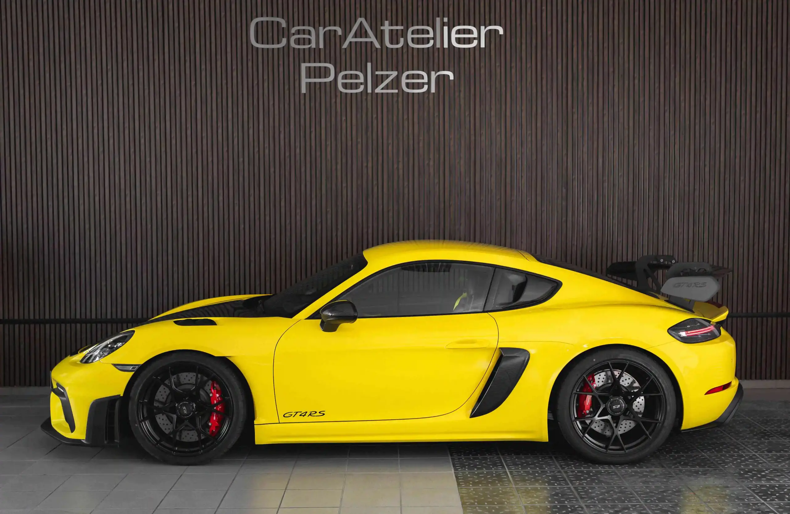 Premiumfahrzeuge kaufen & verkaufen 1 Premiumfahrzeuge kaufen & verkaufen - Gelber Porsche GT4 RS Sportwagen mit schwarzem Heckspoiler und roten Bremssätteln in Seitenansicht
